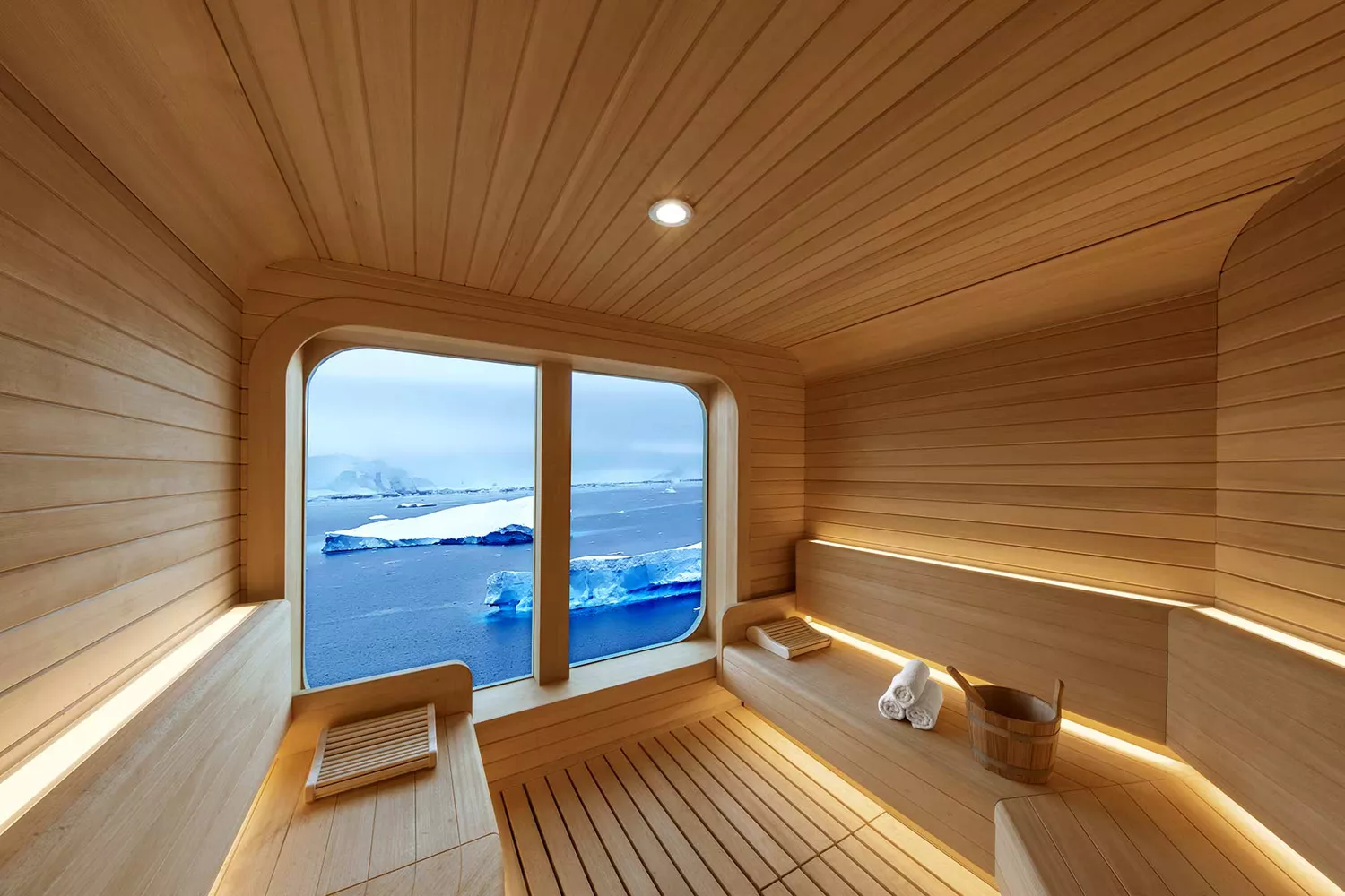 A minimalist, wood-paneled sauna room with large windows overlooking the ocean on the Seabourn Venture.