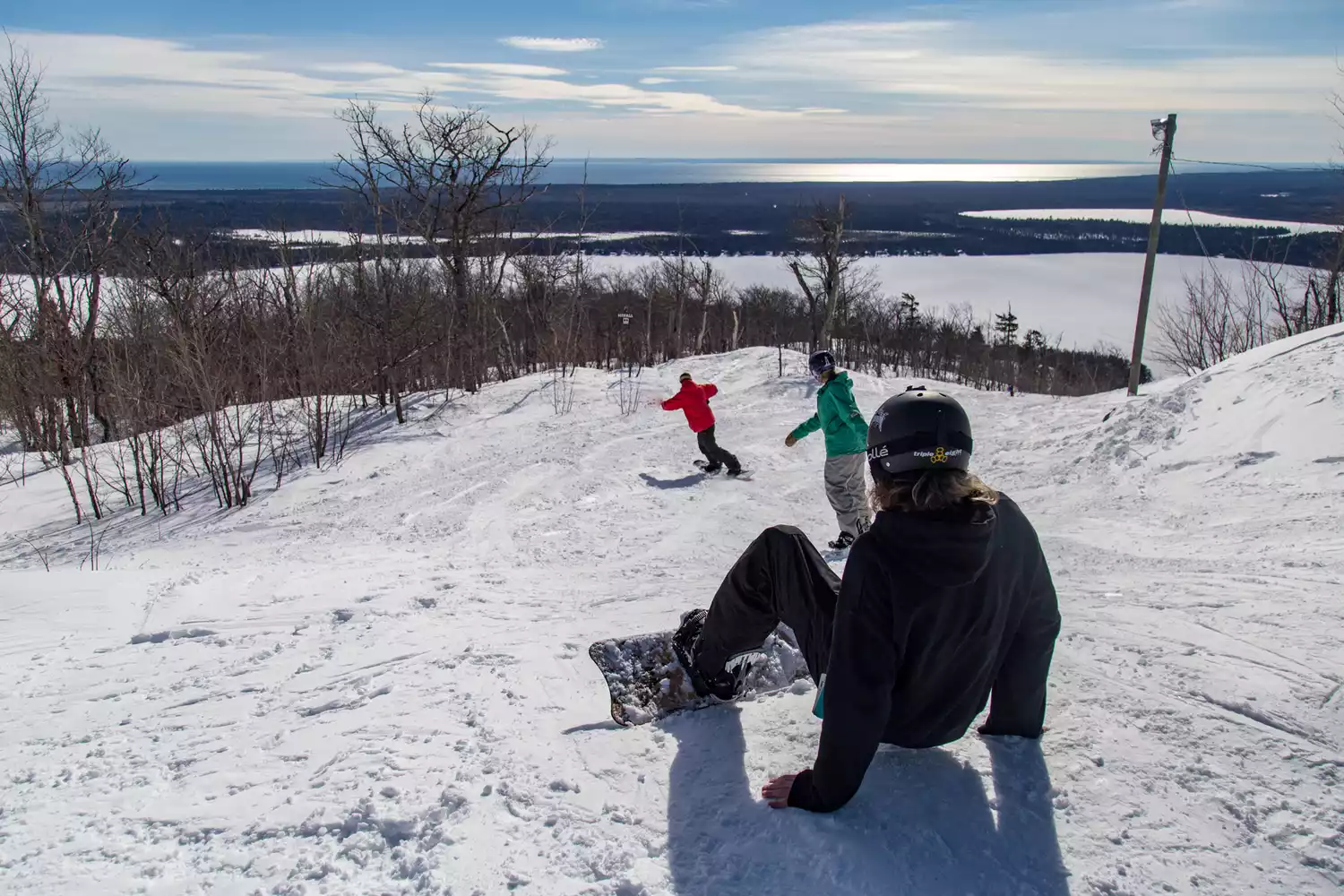 Snowboarders navigating through powder and trees at Mount Bohemia.