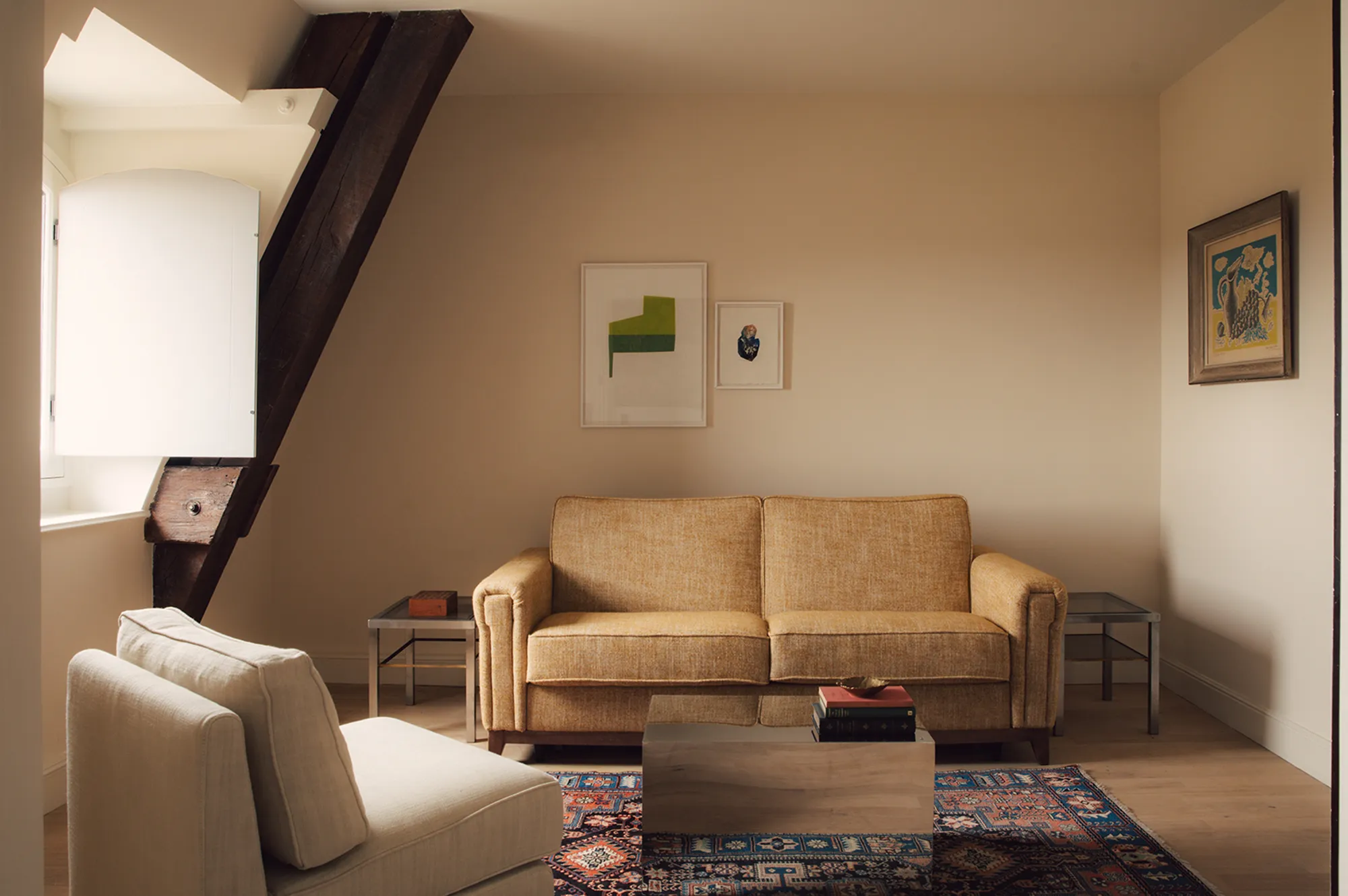A luxury hotel suite with neutral-toned sofas, minimalist furniture, and historic wall art.
