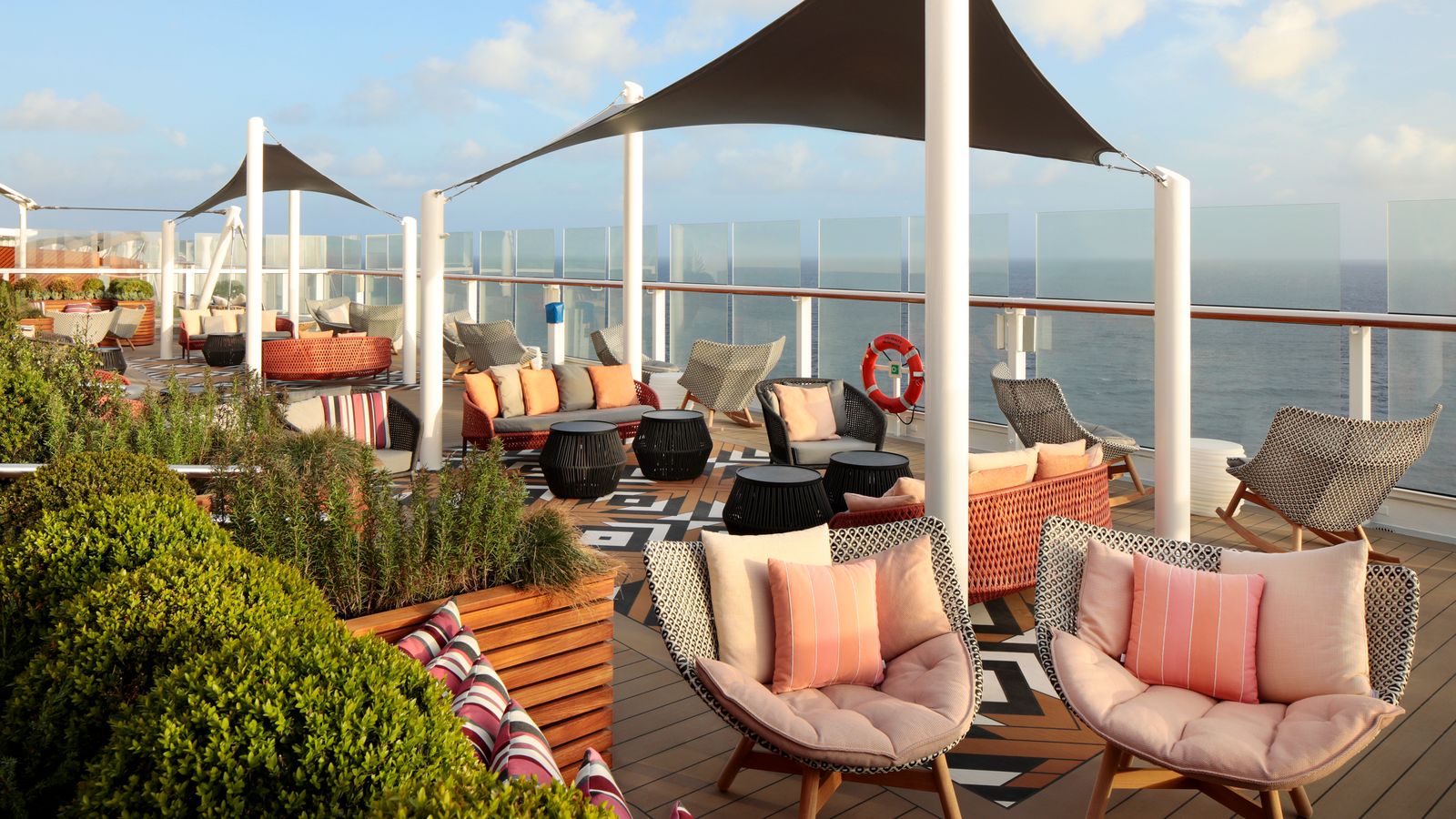 Interiors of a luxury cruise ship lounge featuring elegant furniture and a balcony view.