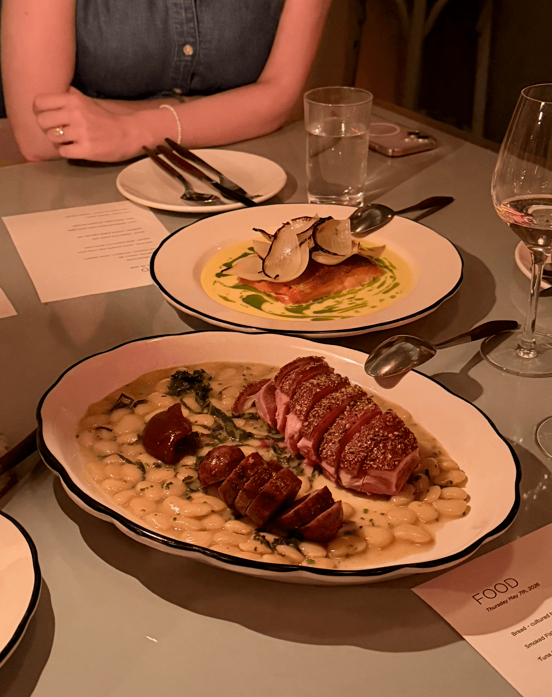 A beautifully plated meal on a restaurant table with cutlery and glassware.