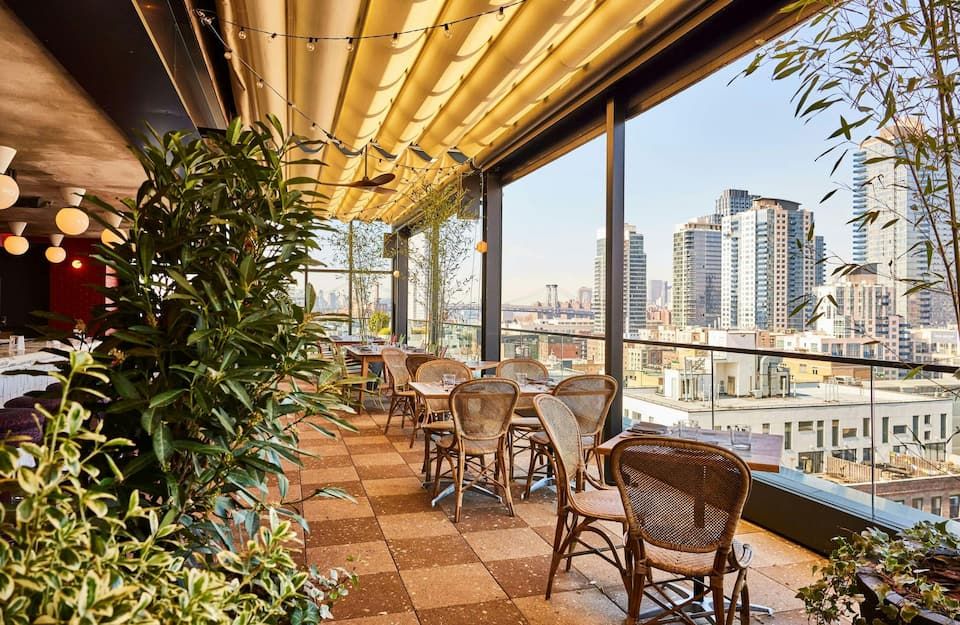 A modern boutique hotel interior featuring a lounge area and a view of the NYC cityscape.
