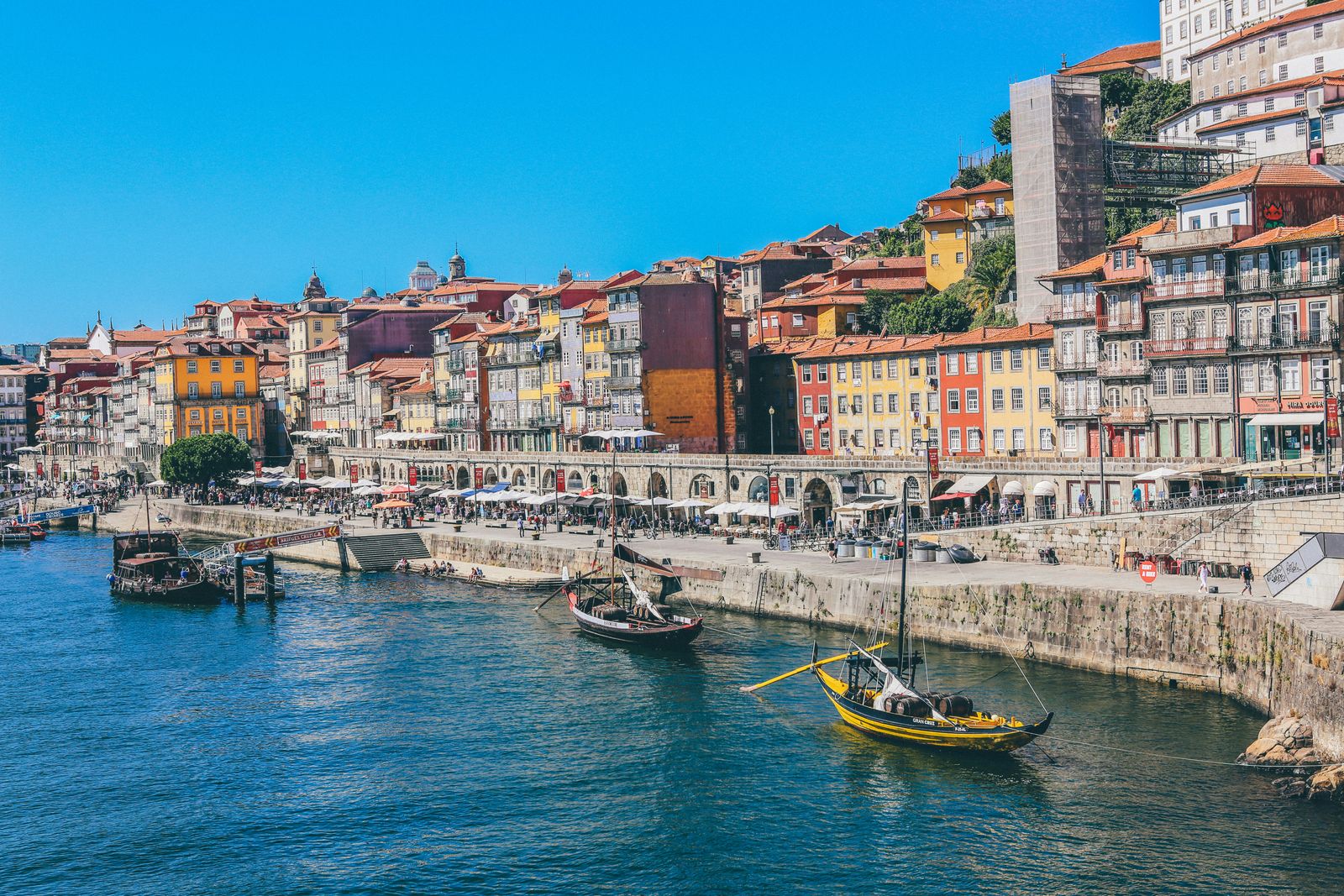 A scenic European waterfront with traditional boats and historic buildings.