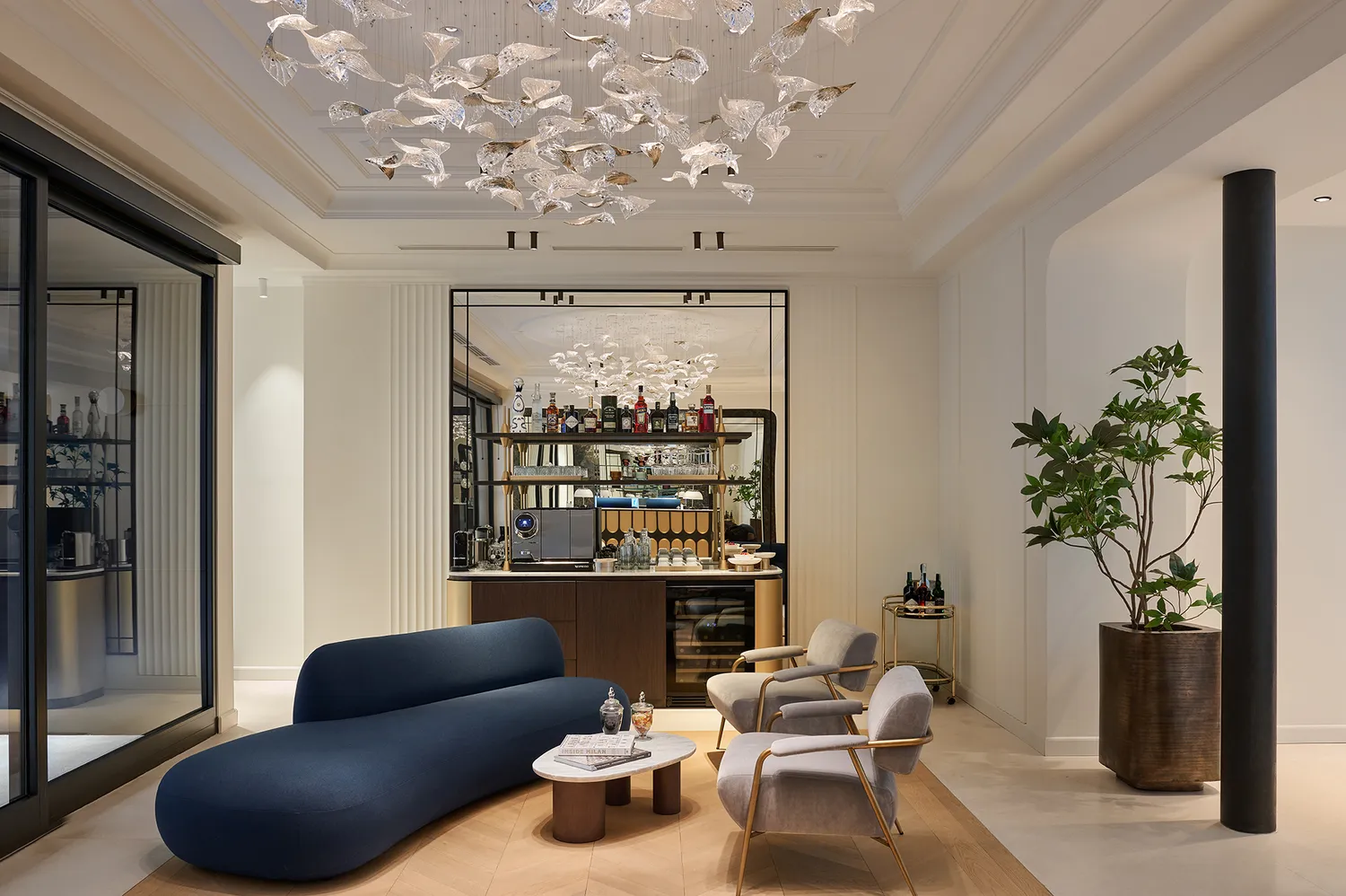 A modern lobby lounge at Casa Laveni featuring a curved sofa, bar counter, and sophisticated decorative lighting.