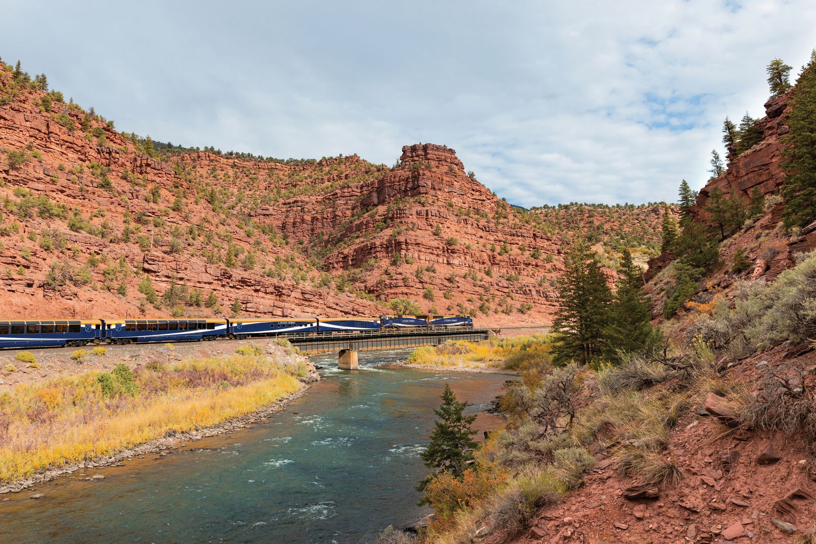 A vast canyon landscape with a winding river and road viewed from an elevated perspective.