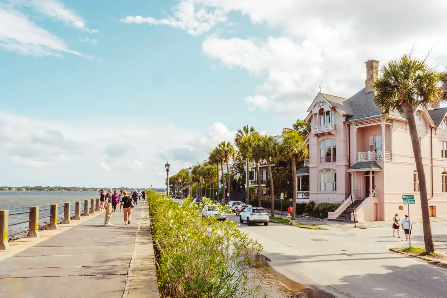 Waterfront street in Charleston with historic architecture and palm trees.