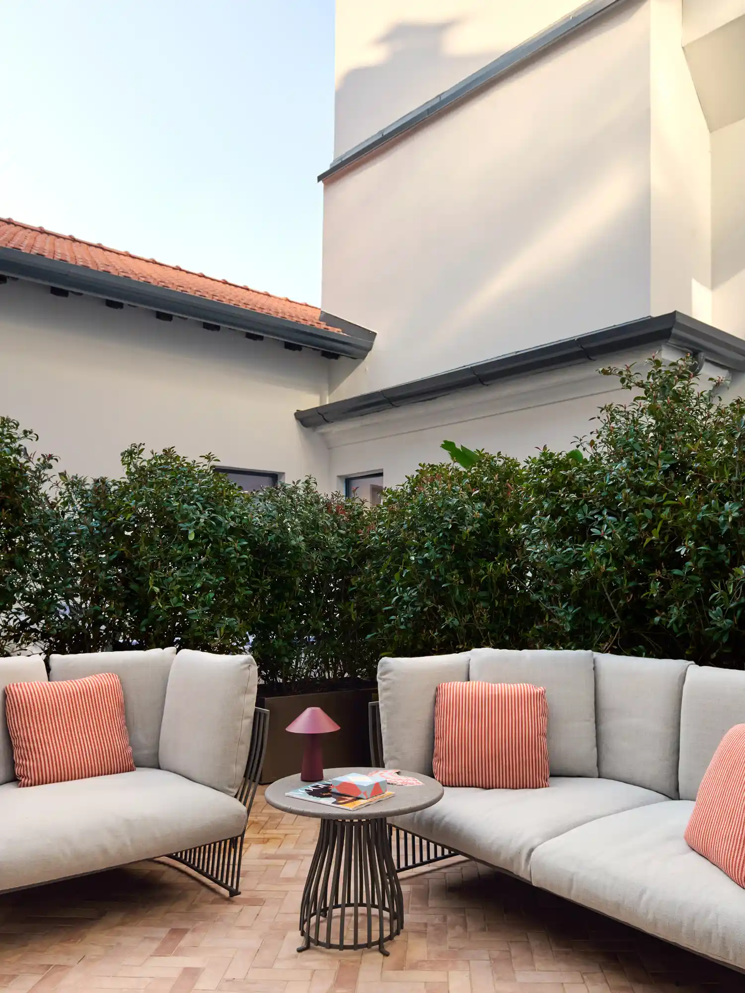 Outdoor terrace seating with sofas and greenery overlooking Milan.