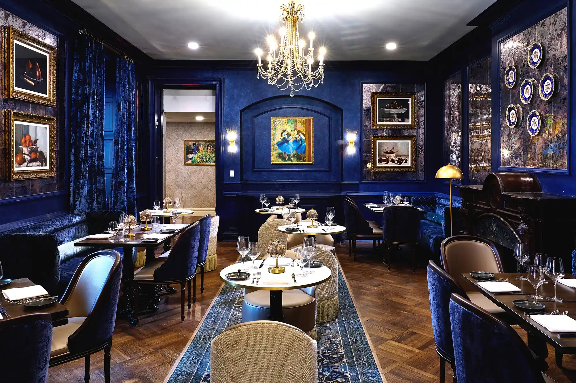 An upscale dining room with elegant table settings and ornate chandeliers.