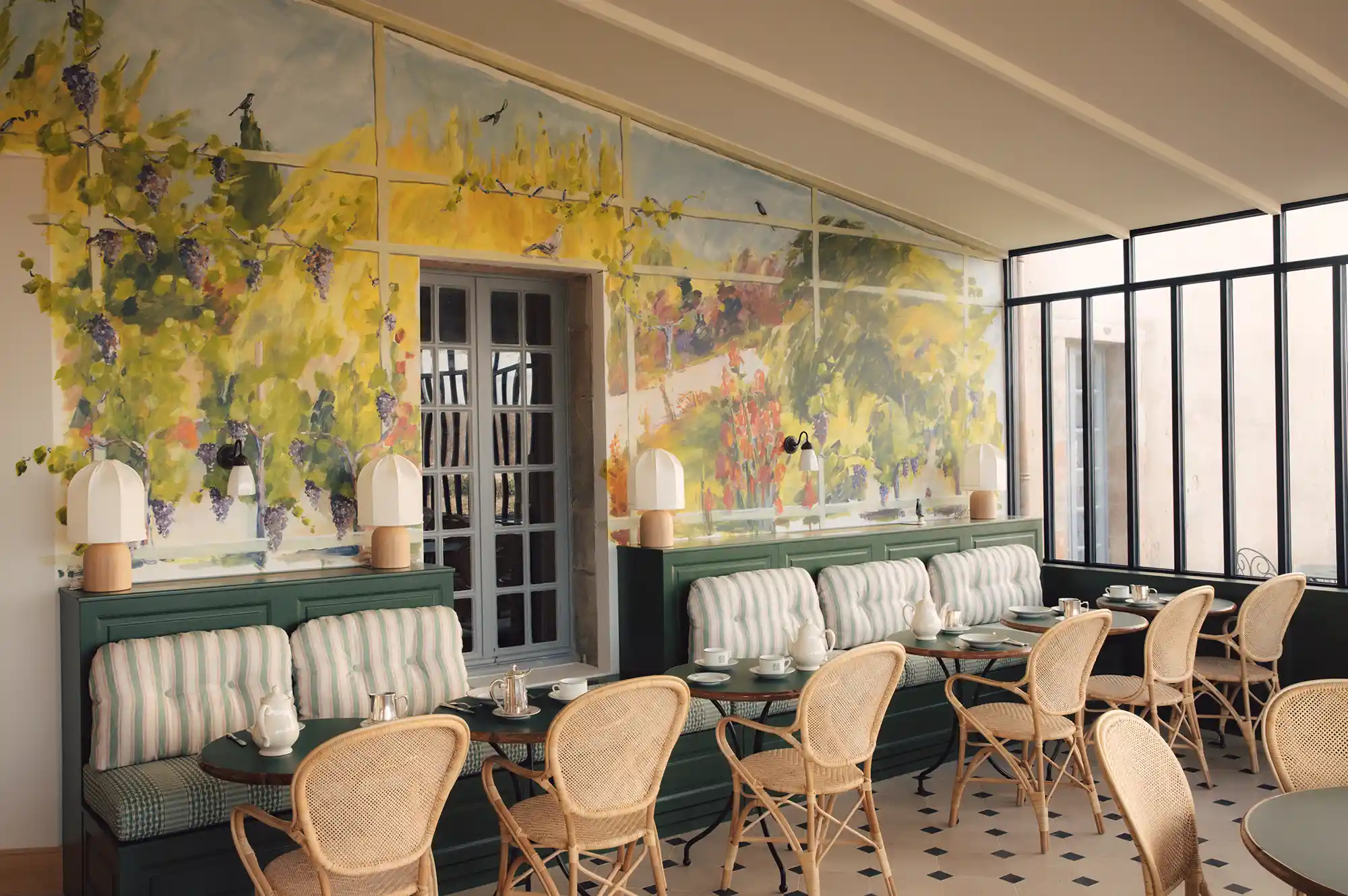 The hotel's dining room with rattan bistro chairs, arched windows, and light-filled interiors.