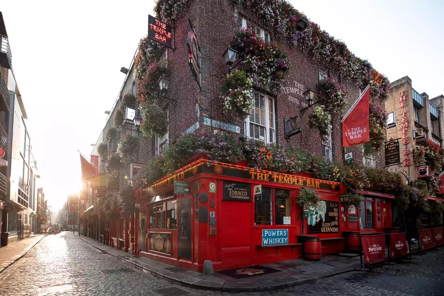 The iconic Temple Bar building on a cobblestone street corner in Dublin at sunset.
