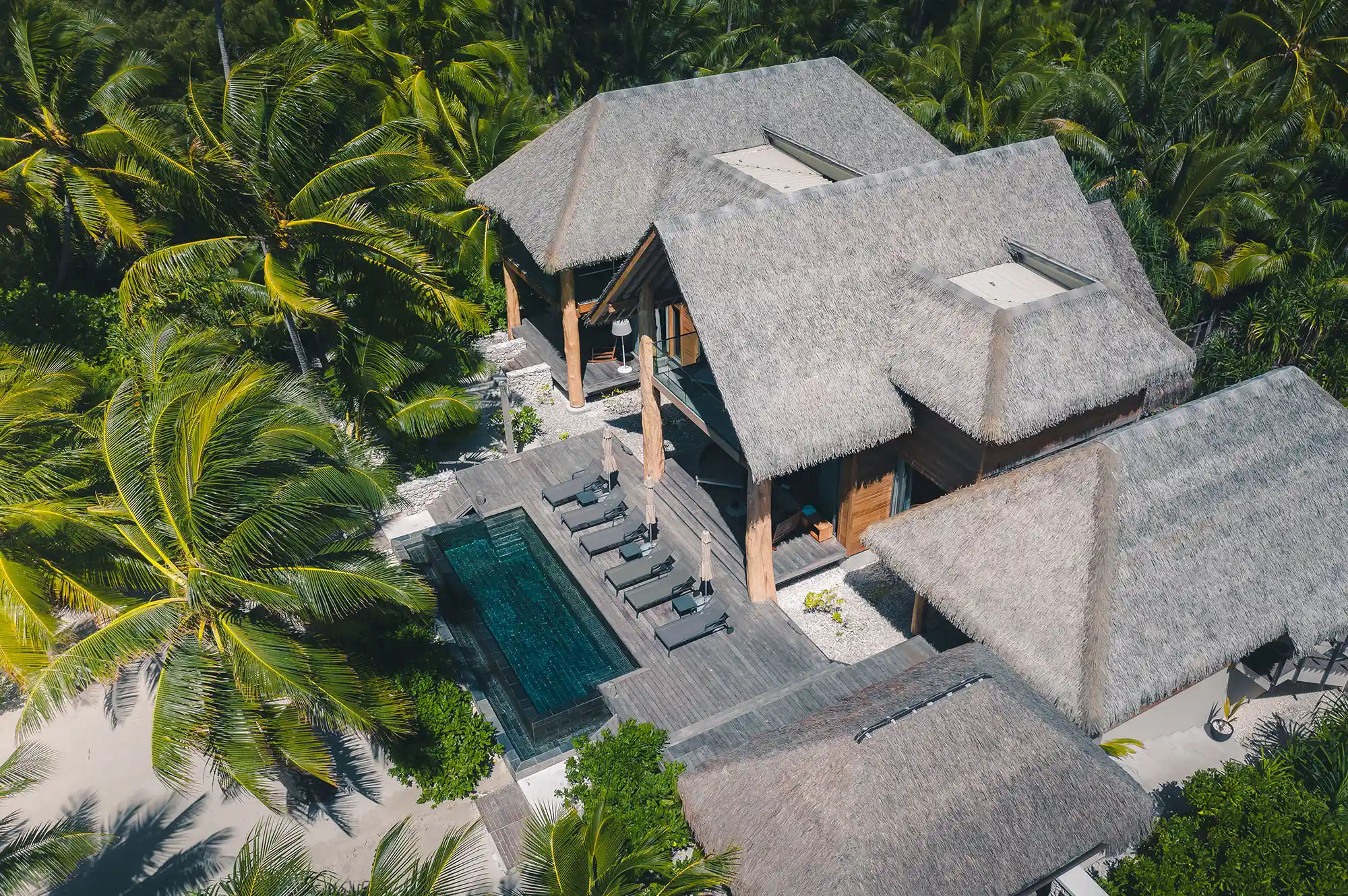 A luxury villa featuring a private swimming pool and traditional thatched-roof architecture.