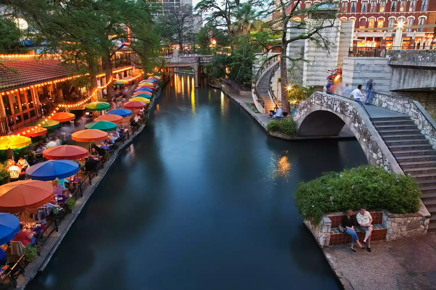 The San Antonio River Walk at dusk with lit pathways and architectural charm.