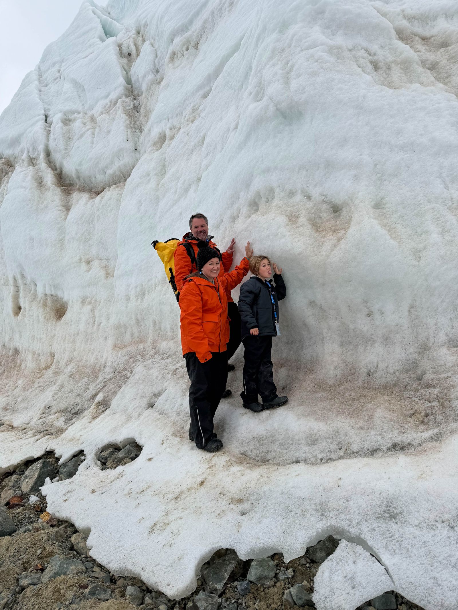 An adventurer walking across a snowy glacial landscape with a backpack and hiking poles.