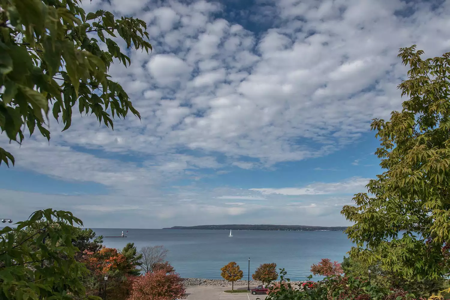 A white sailboat gliding across the blue waters of Little Traverse Bay in Petoskey.