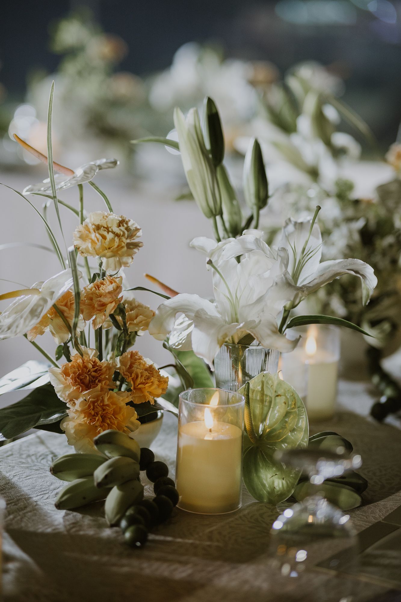 A minimalist floral arrangement with greenery and elegant candles on a reception table.
