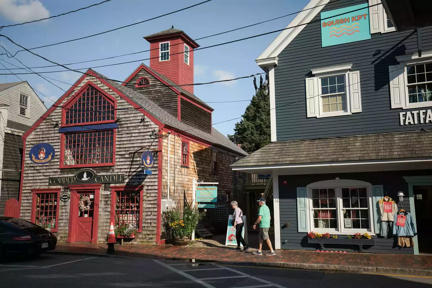 A couple walking past historic storefronts in the downtown area of Kennebunkport, Maine.