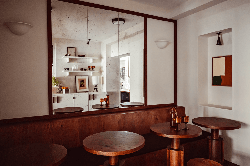 Minimalist white-walled hotel room with heavy oak furniture and artistic details.