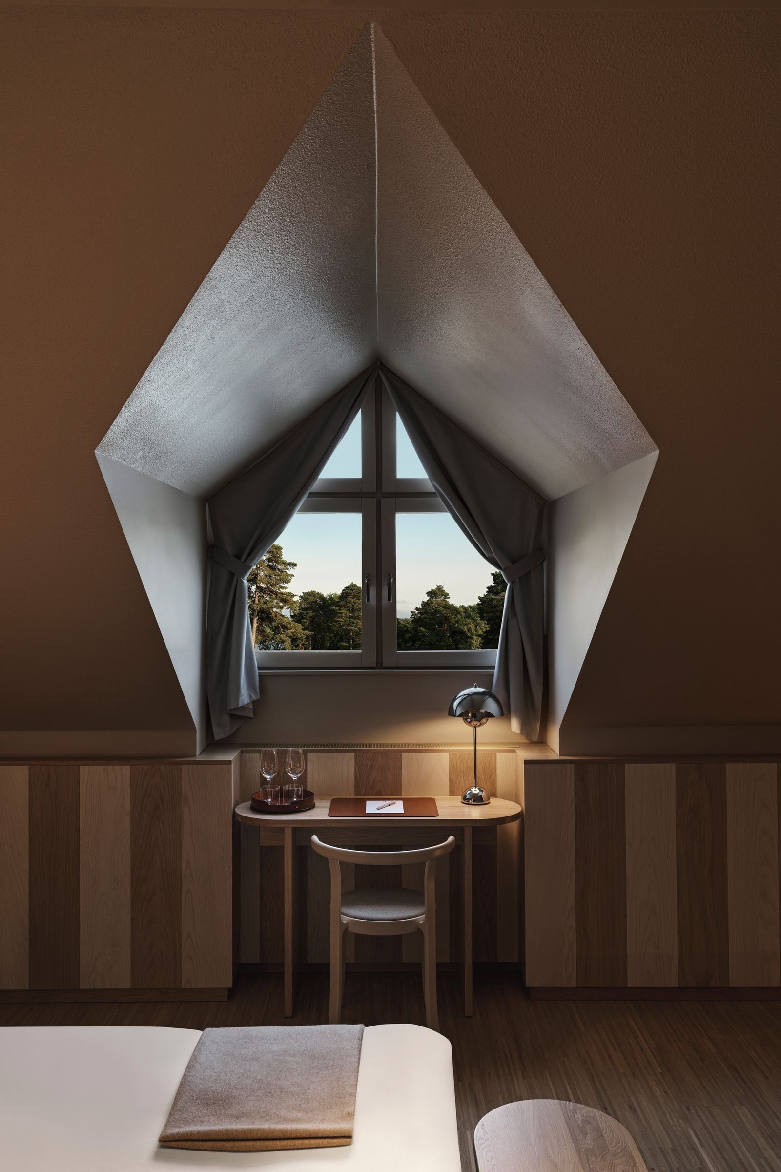 A contemporary interior featuring a designer desk and chair with soft natural window light.