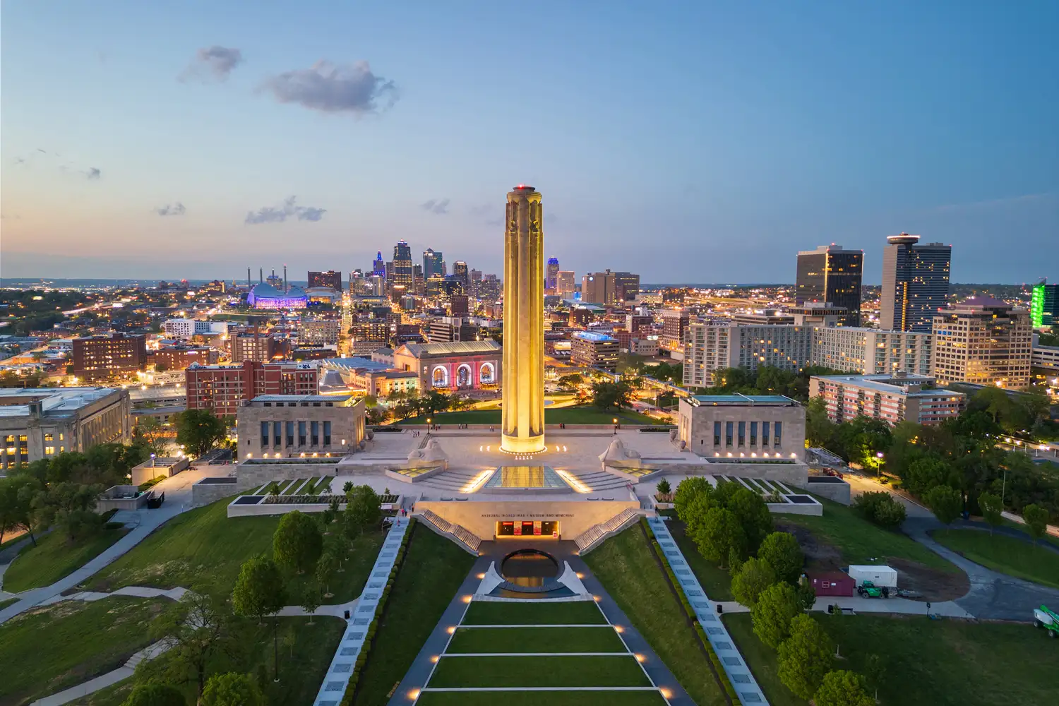 Nighttime view of the Kansas City skyline with the National WWI Museum and Memorial illuminated in the foreground.