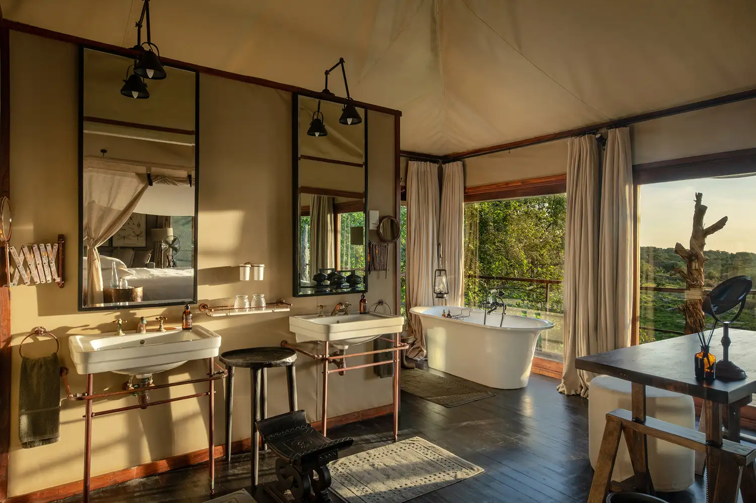 A luxurious bathroom in Mwiba Lodge featuring a freestanding tub with a view of the Tanzanian landscape.