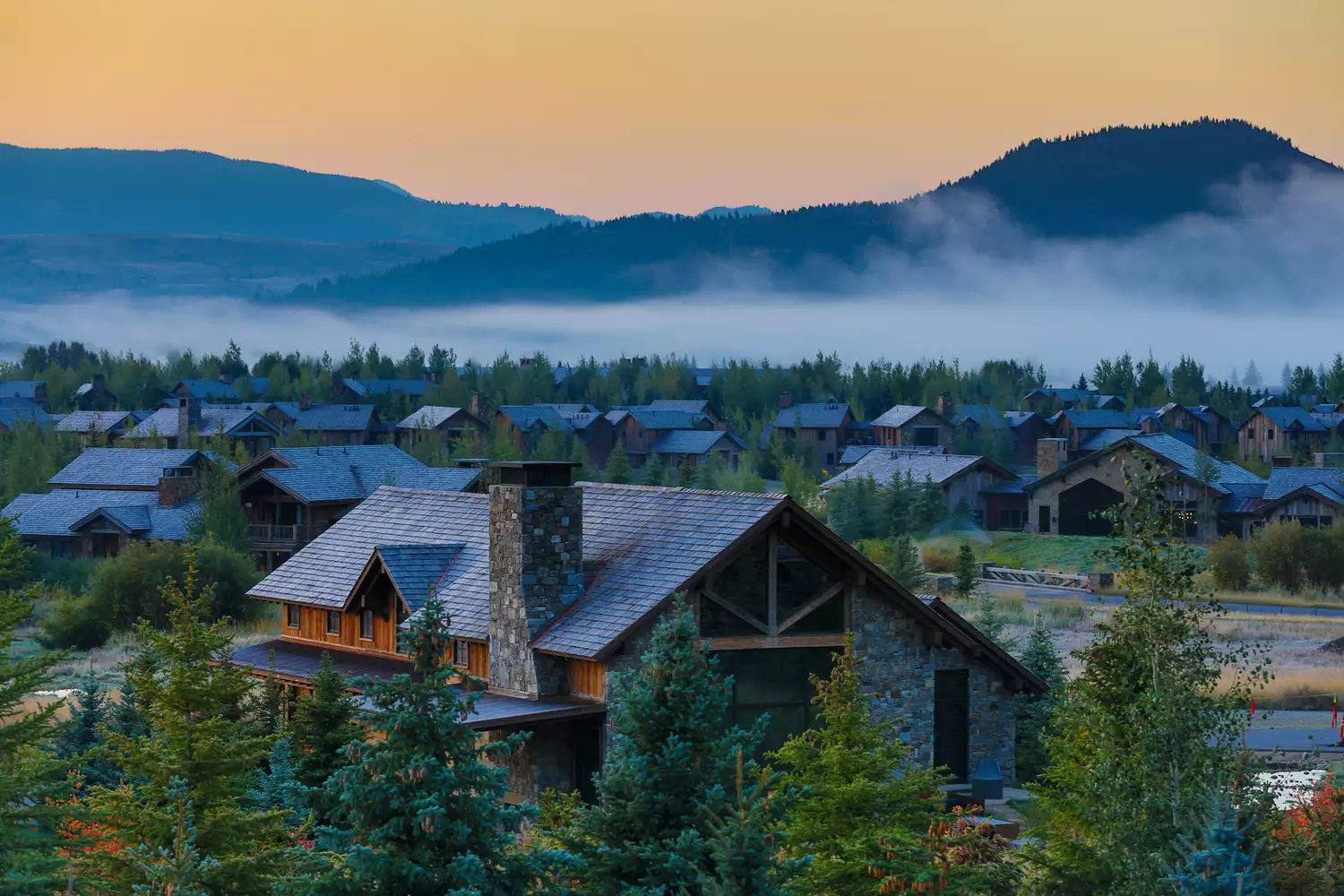 Morning fog rolling through a residential valley in Jackson, Wyoming surrounded by mountains.