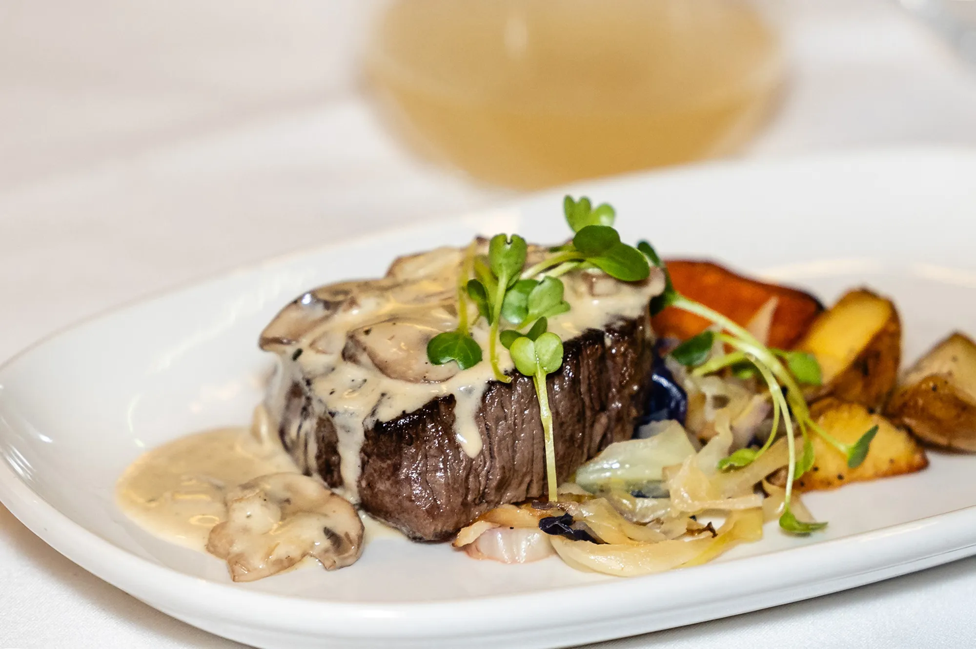 A close-up of a premium steak dish with roasted vegetables and rich sauce.