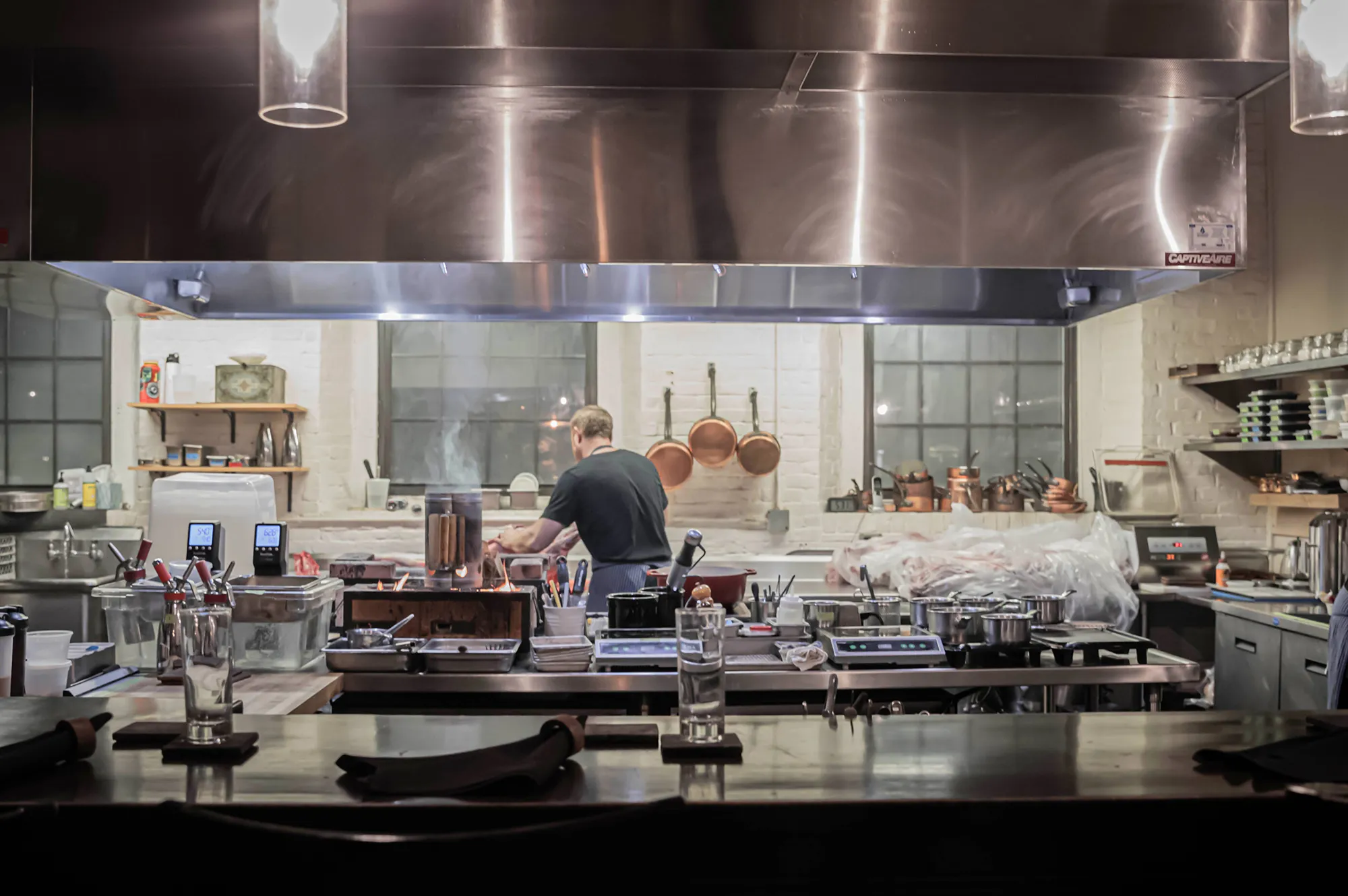 A professional chef preparing gourmet dishes in an open kitchen at Stages at One Washington.
