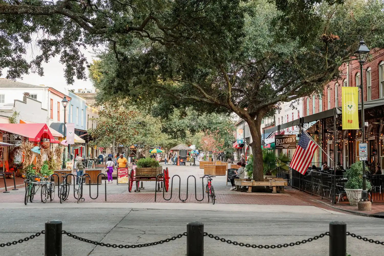 A charming pedestrian street in Savannah Georgia lined with shops and mature trees.