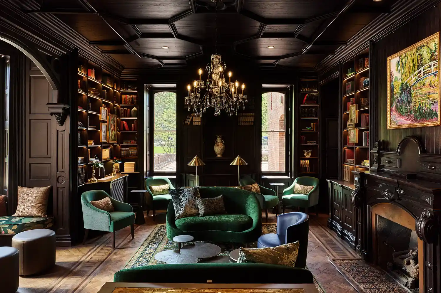 A cozy library room with bookshelves, leather sofas, and a fireplace.
