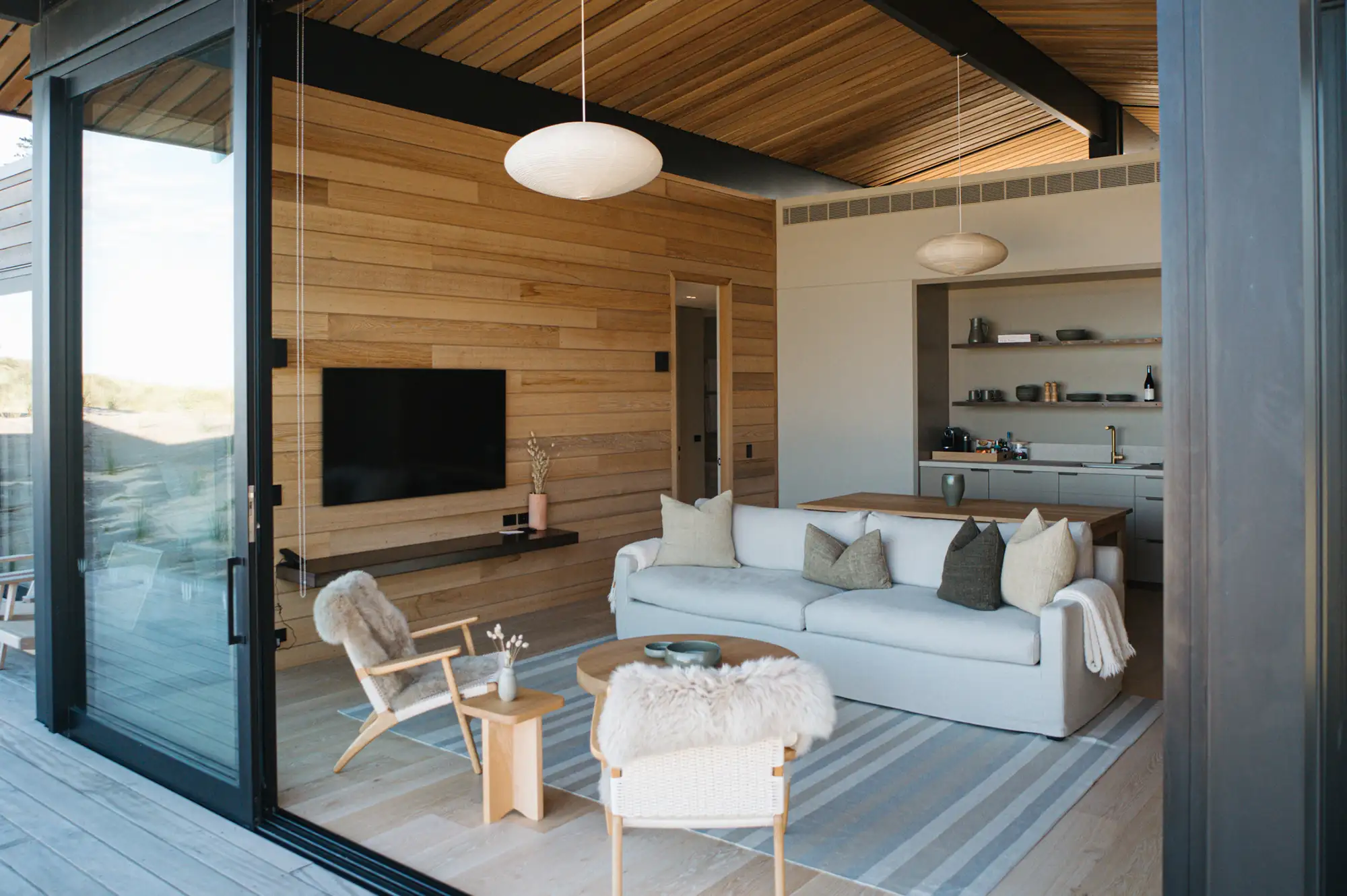 Modern luxury living room featuring pale oak wood paneling, linen sofas, and a minimalist aesthetic.