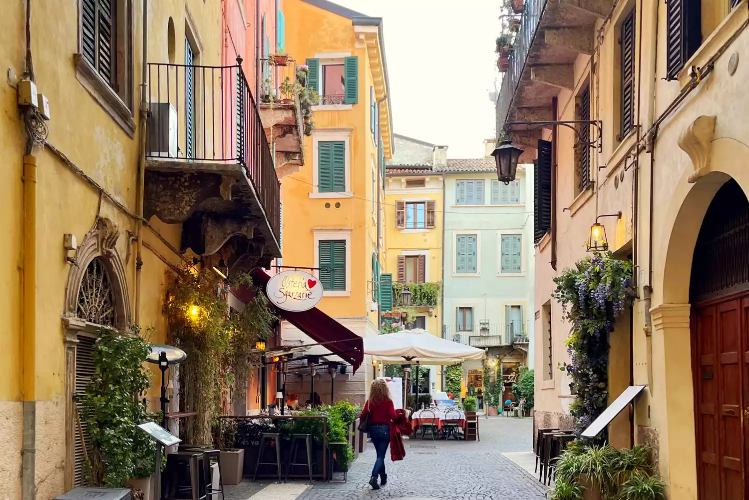 A woman walking through a narrow, historic stone street in Verona's Città Antica.