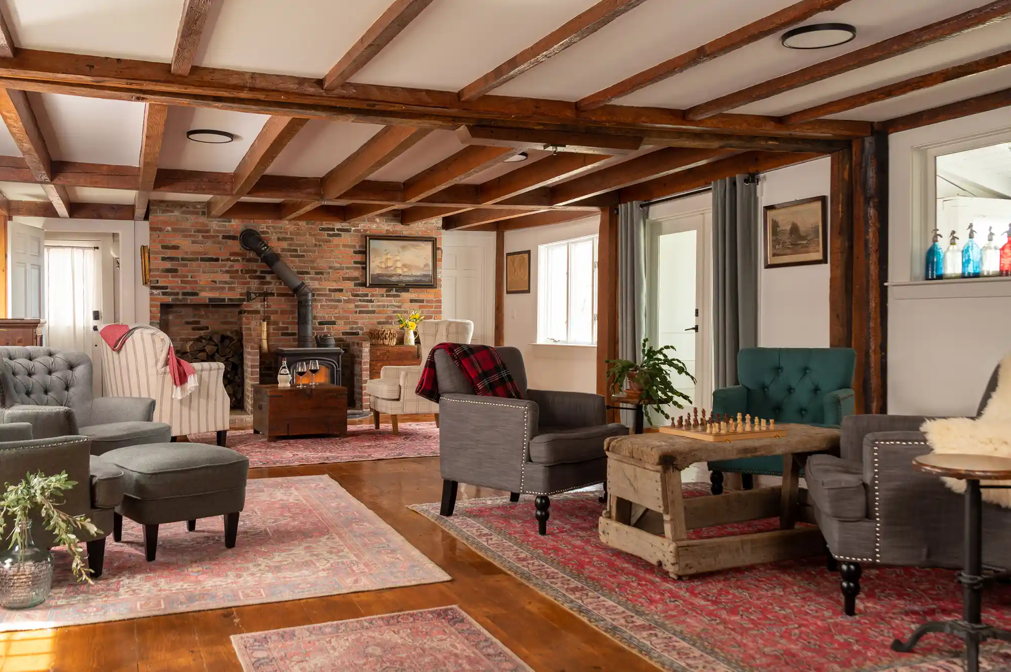 A cozy restaurant interior featuring wooden beams, a fireplace, and comfortable seating.