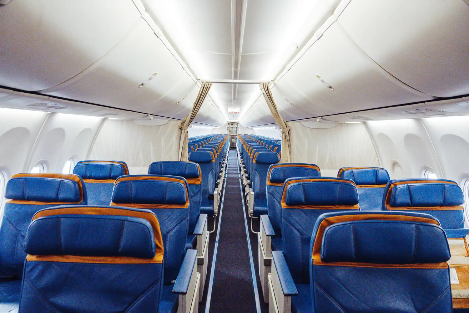 Interior cabin of a Cayman Airways Boeing 737-8 MAX featuring blue passenger seating.