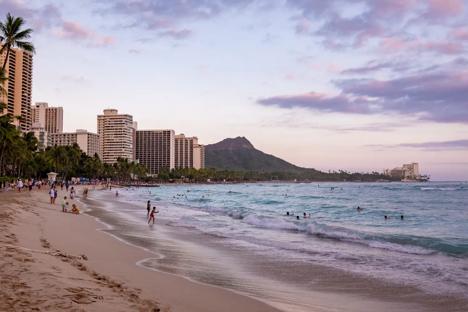 Diamond Head crater and beach goers in Honolulu during sunset.