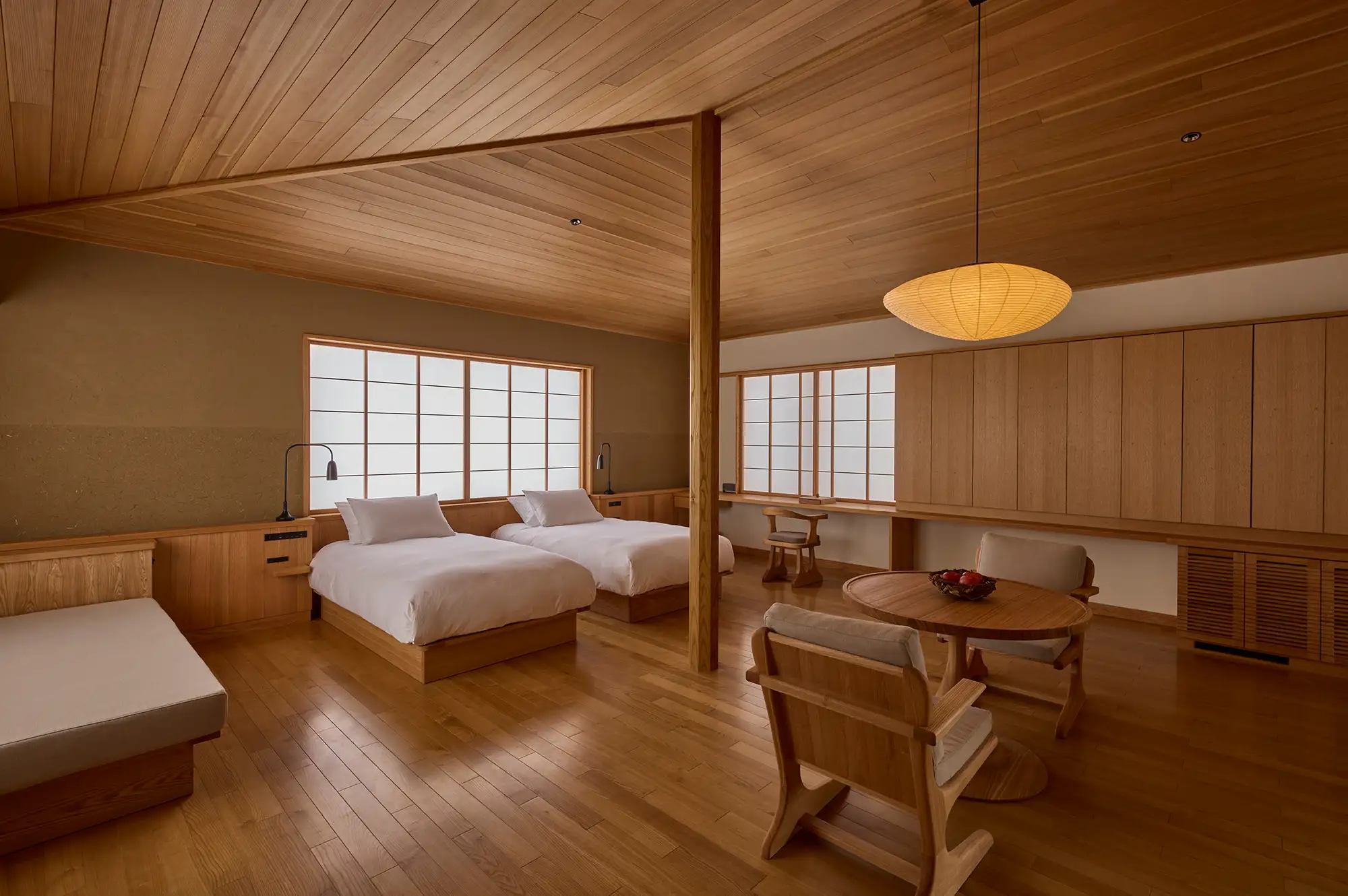A spacious guest villa interior at Azuma Farm Koiwai with minimalist wooden furniture and twin beds.