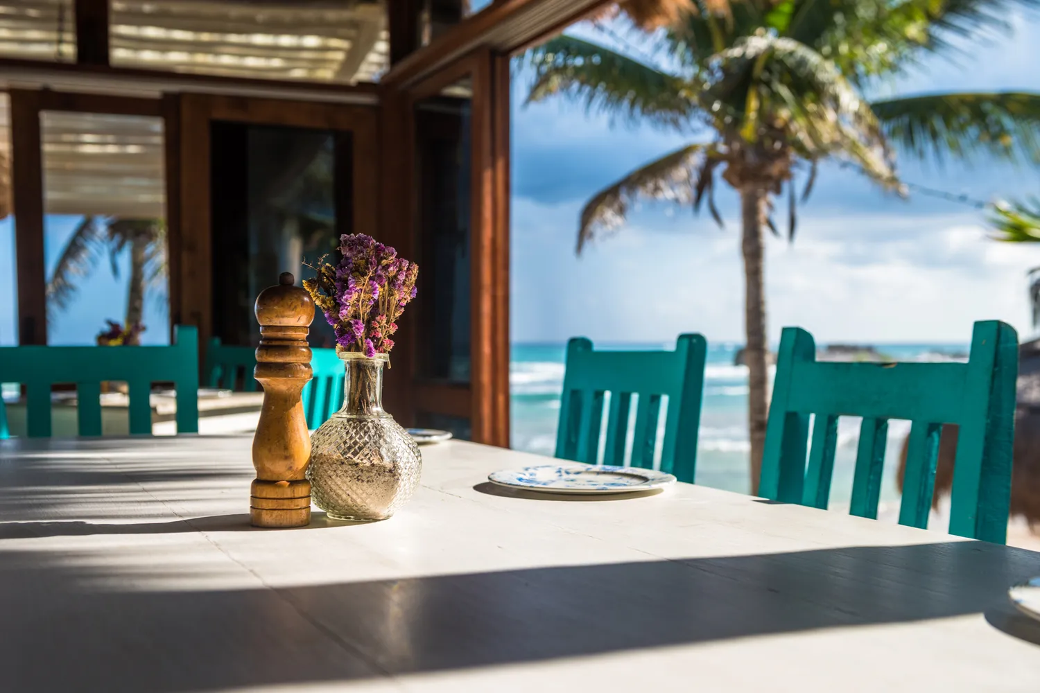 A beautifully set restaurant table under palm trees at dusk in Tulum.