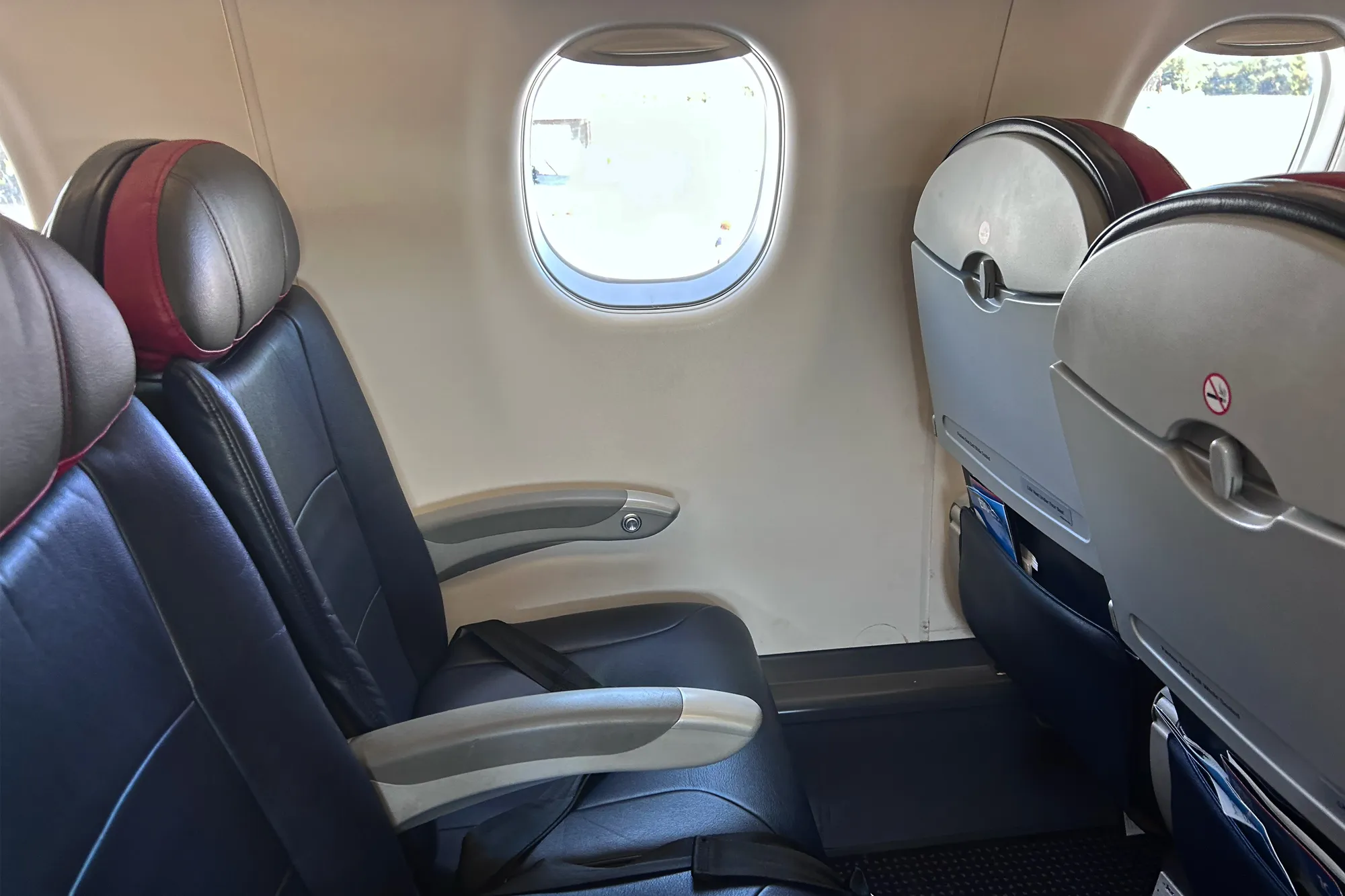 A close-up of passenger seats next to a window inside a modern airplane cabin.