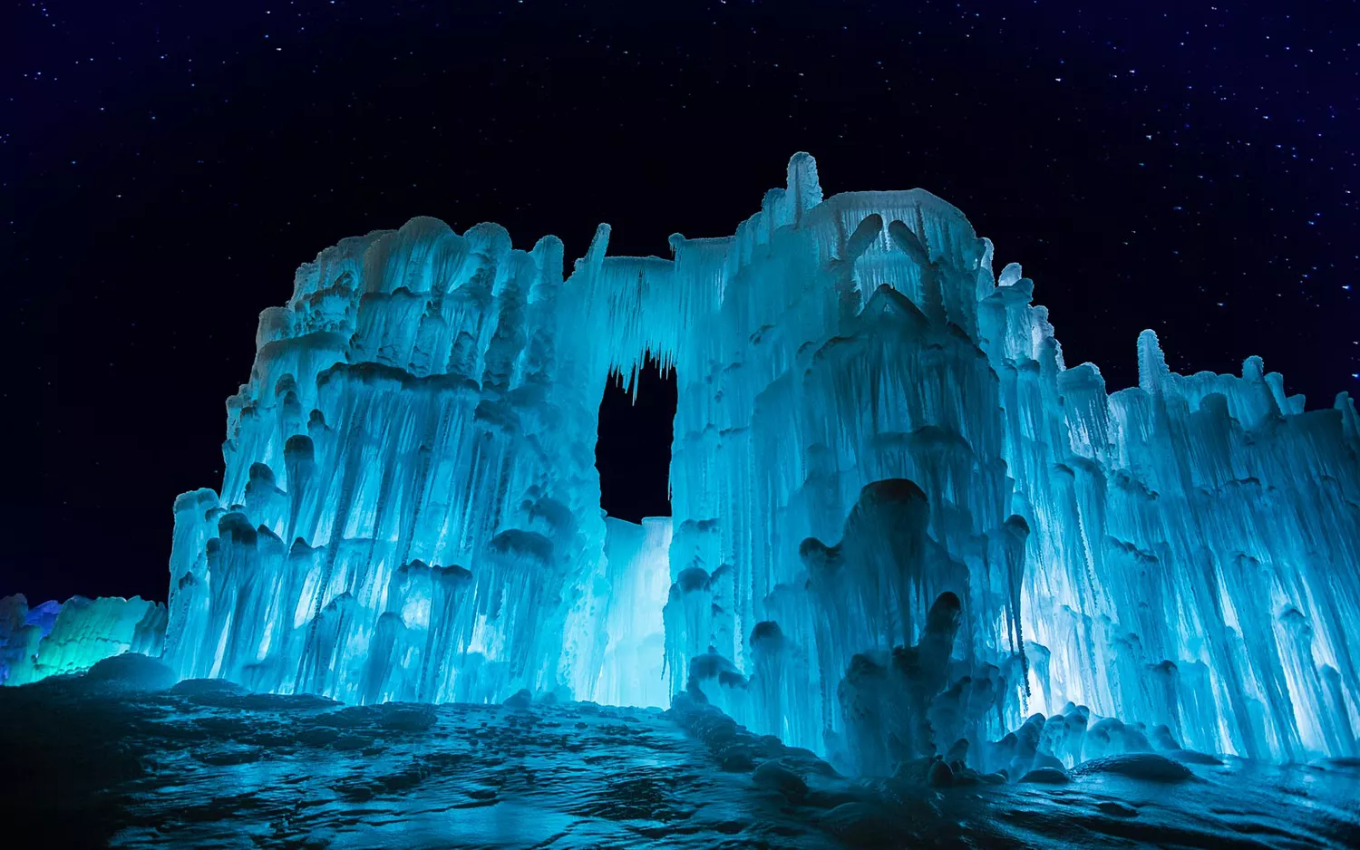 An illuminated blue ice structure glowing against a dark night sky.