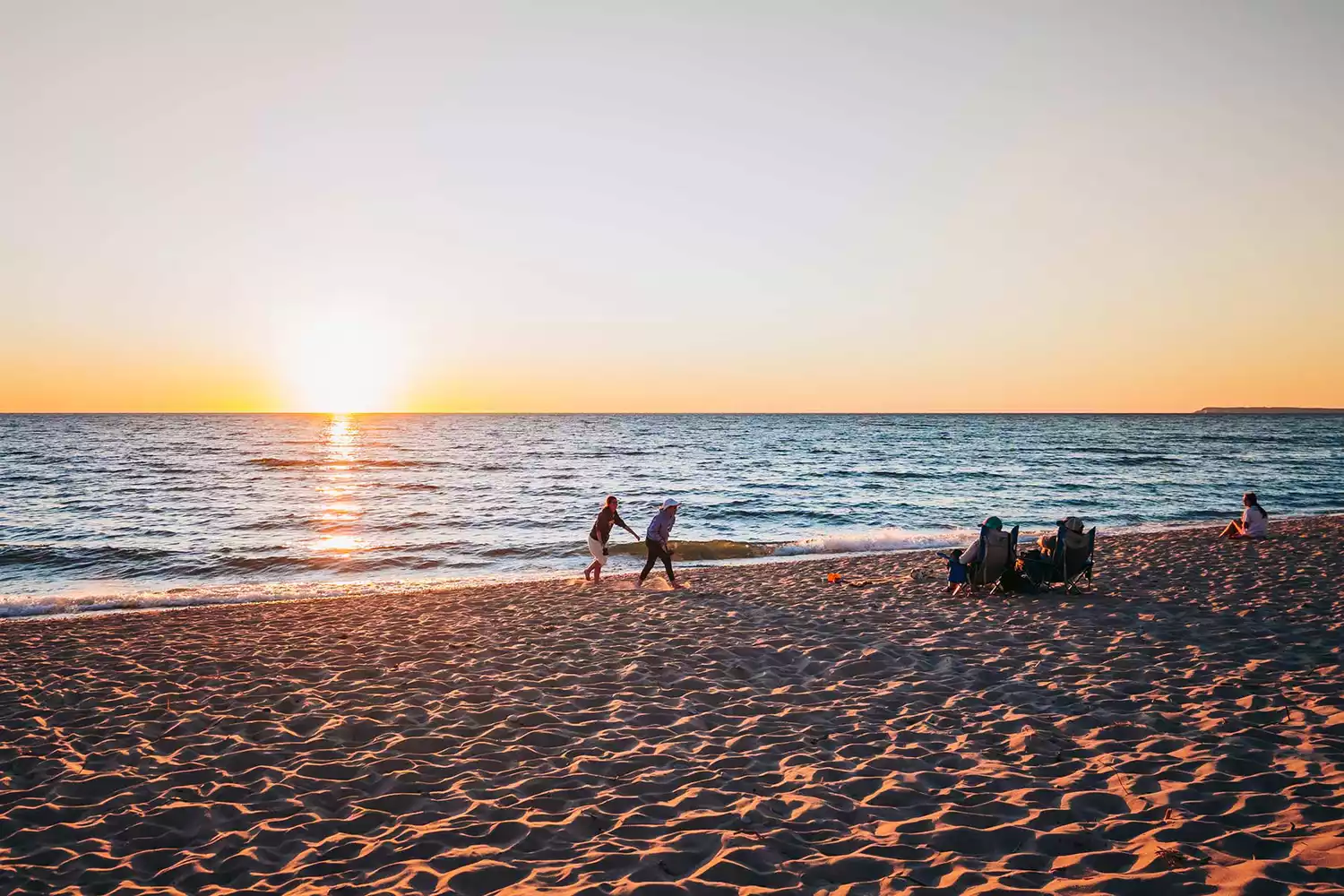 Tourists walking along the sandy shoreline and turquoise waters of Empire Beach.