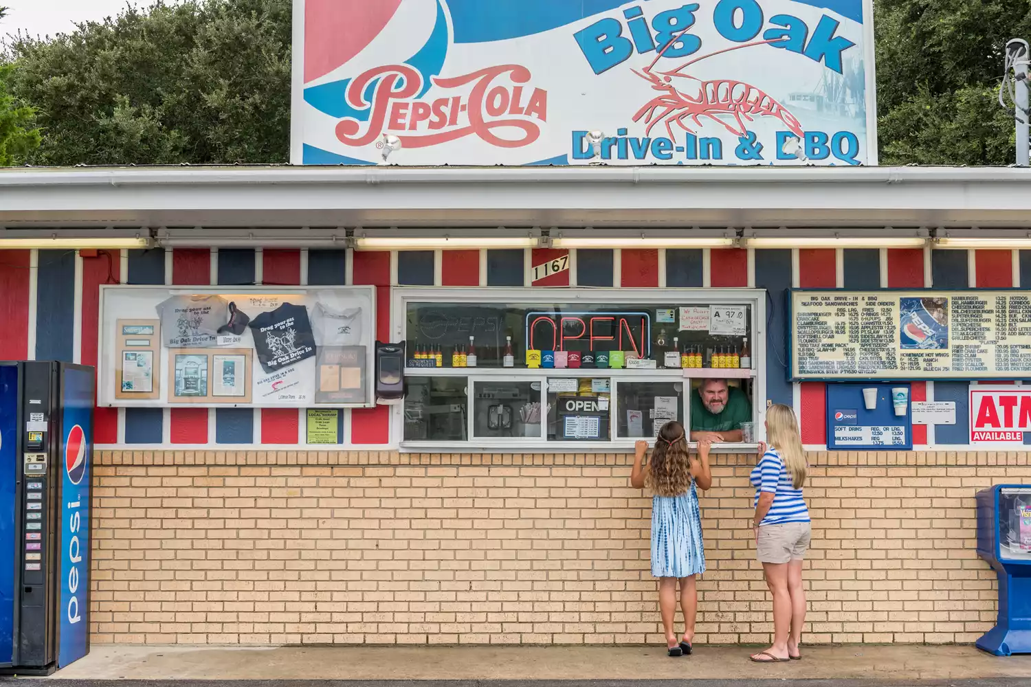 Family ordering food at the window of the Big Oak Drive-In barbecue and seafood restaurant.
