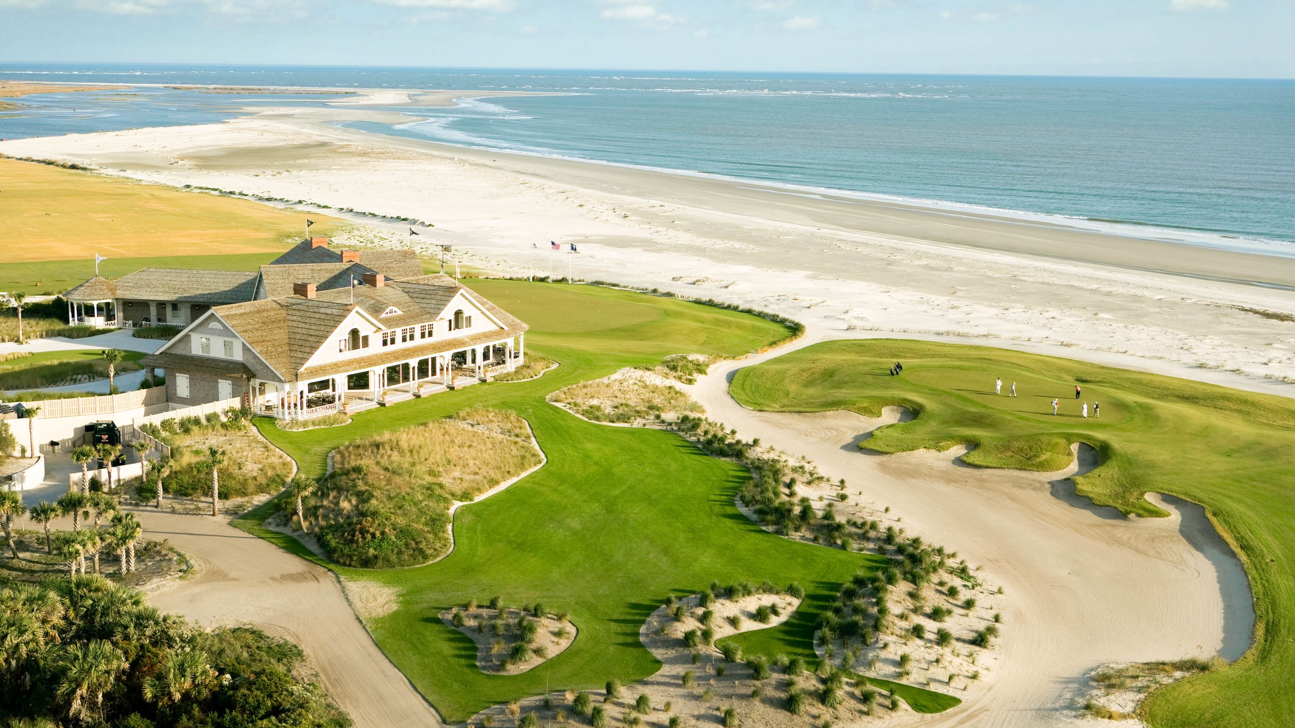 Aerial view of coastal architecture and luxury housing along a sunny shoreline.